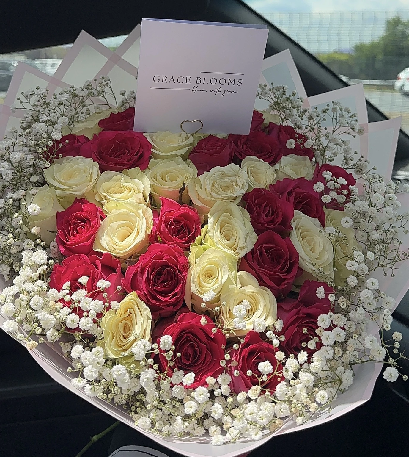 Crimson and ivory roses with delicate baby's breath and a Grace Blooms card