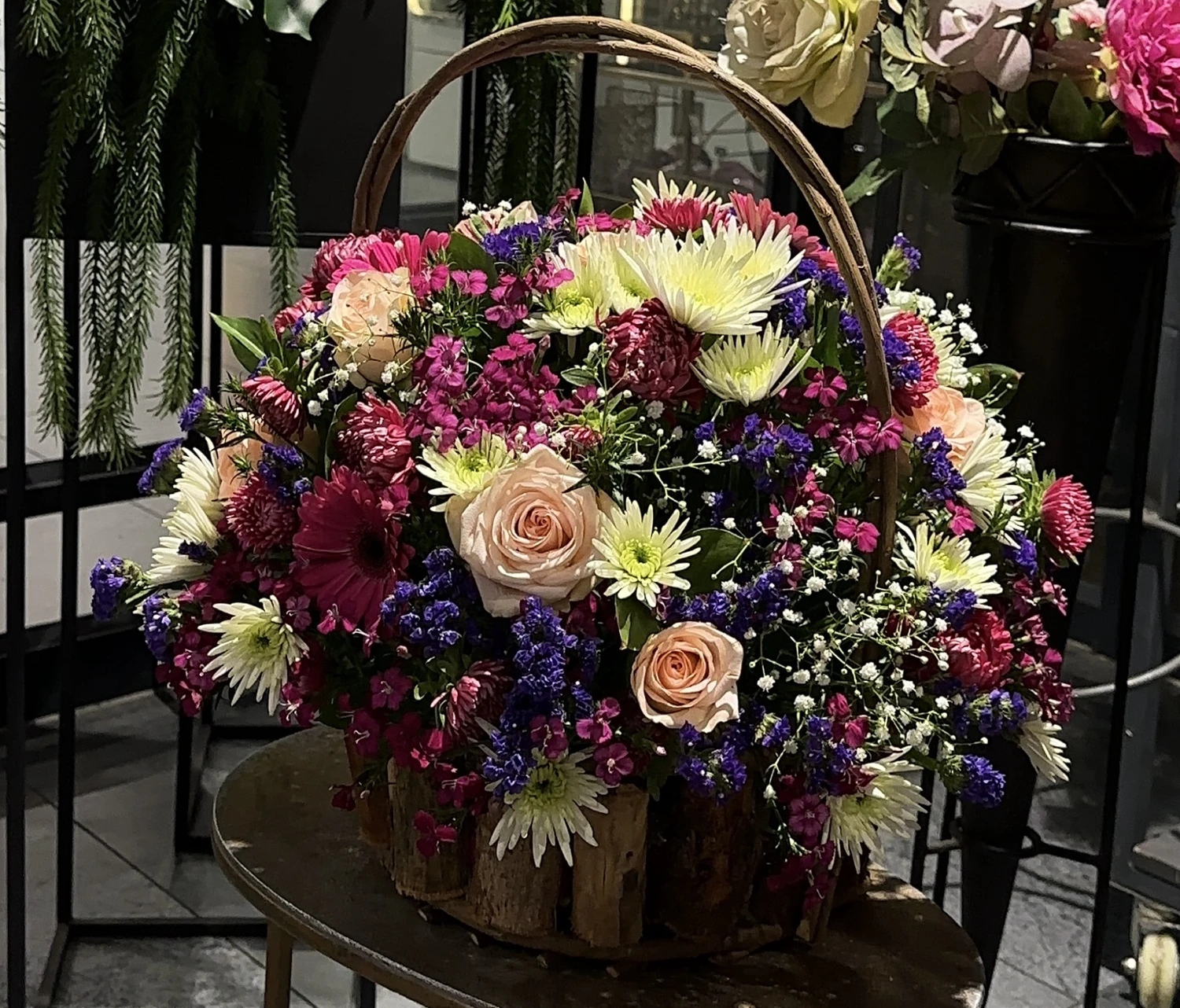 A colourful sympathy basket composed of pink, cream and purple flowers with greenery