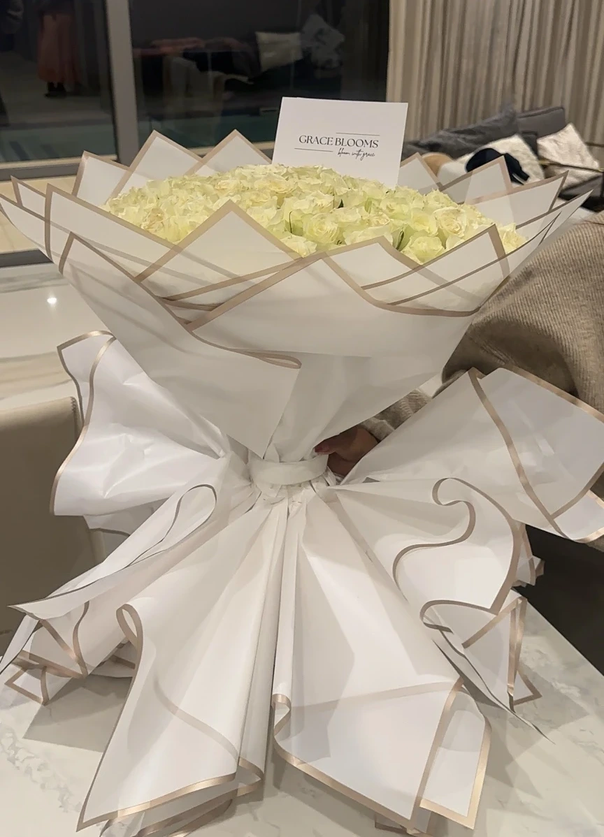 An angled view of the white rose bouquet and its sculptural wrapping